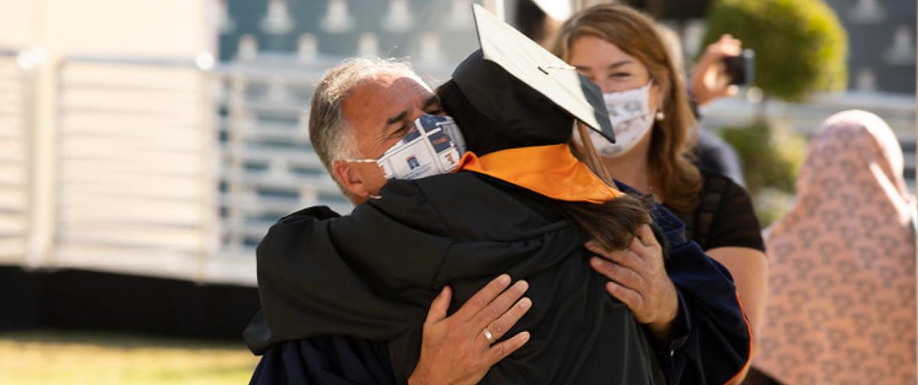 President Fram Virjee hugging student during graduation.